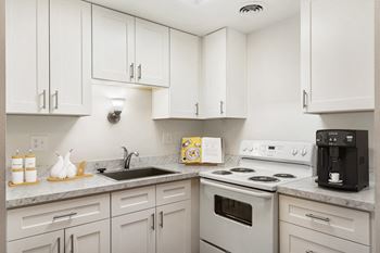 a kitchen with white cabinets and white appliances and a sink  at Park View Apartments, Washington, 98801